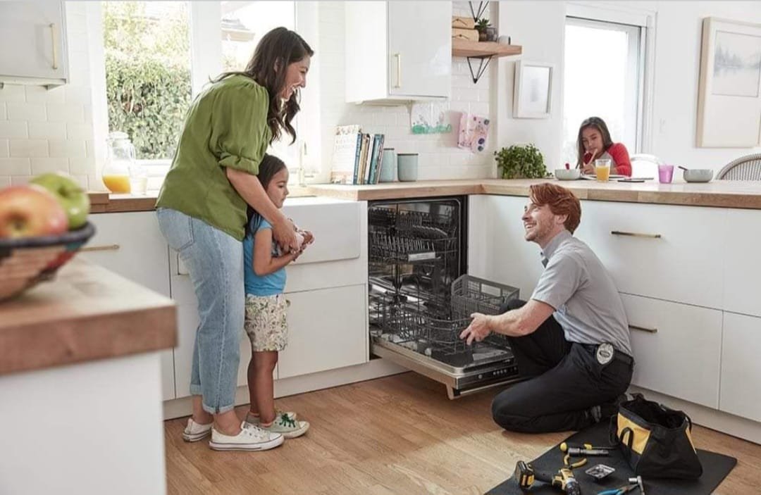 Technician repairing a dishwasher in a home kitchen
